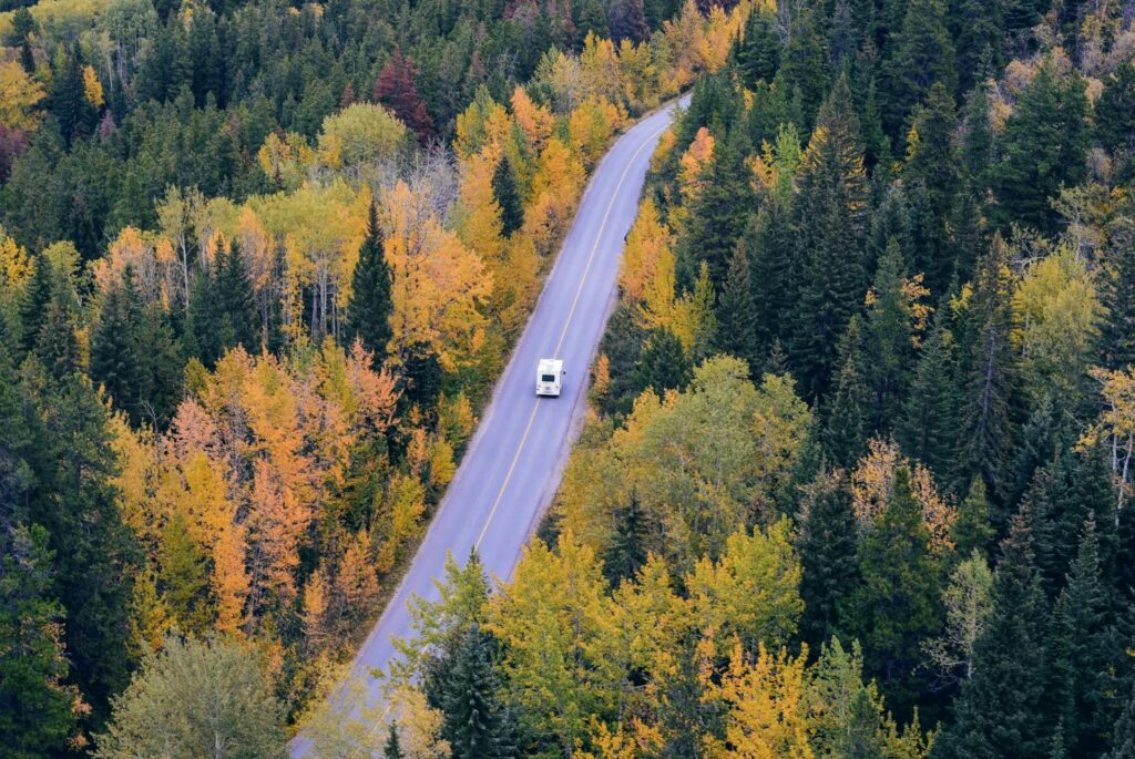 Rv on an open road surrounded by yellow trees